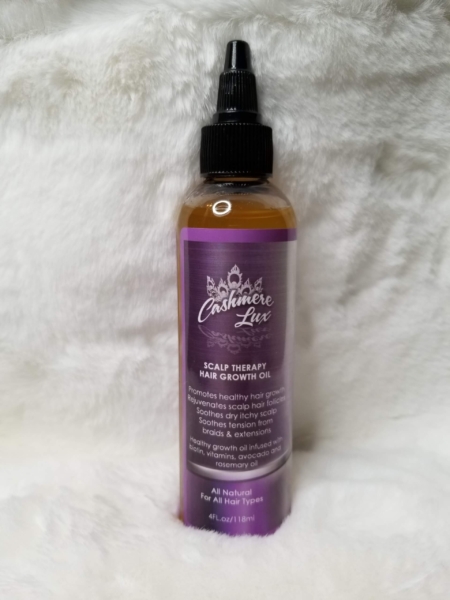A bottle of Scalp Therapy Growth Oil on a white fur rug.