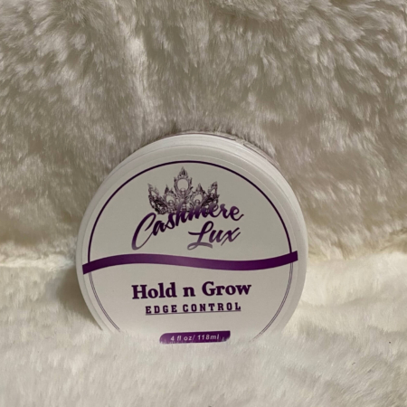 A jar of Hold n Grow Edge Control on a white furry surface.