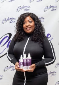 A picture of a woman with curly hair holding some hair products